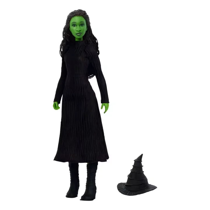 Elphaba doll standing in her long black gown and boots with her pointed witch’s hat placed beside her on a white background