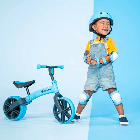 Child standing beside Yvolution Velo Junior Balance Bike Blue
